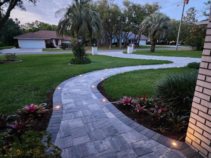 A walkway in front of a house with lights on it