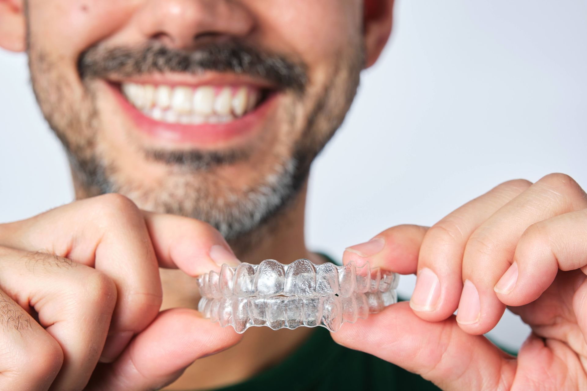 Person holding a clear dental aligner for orthodontic teeth straightening.