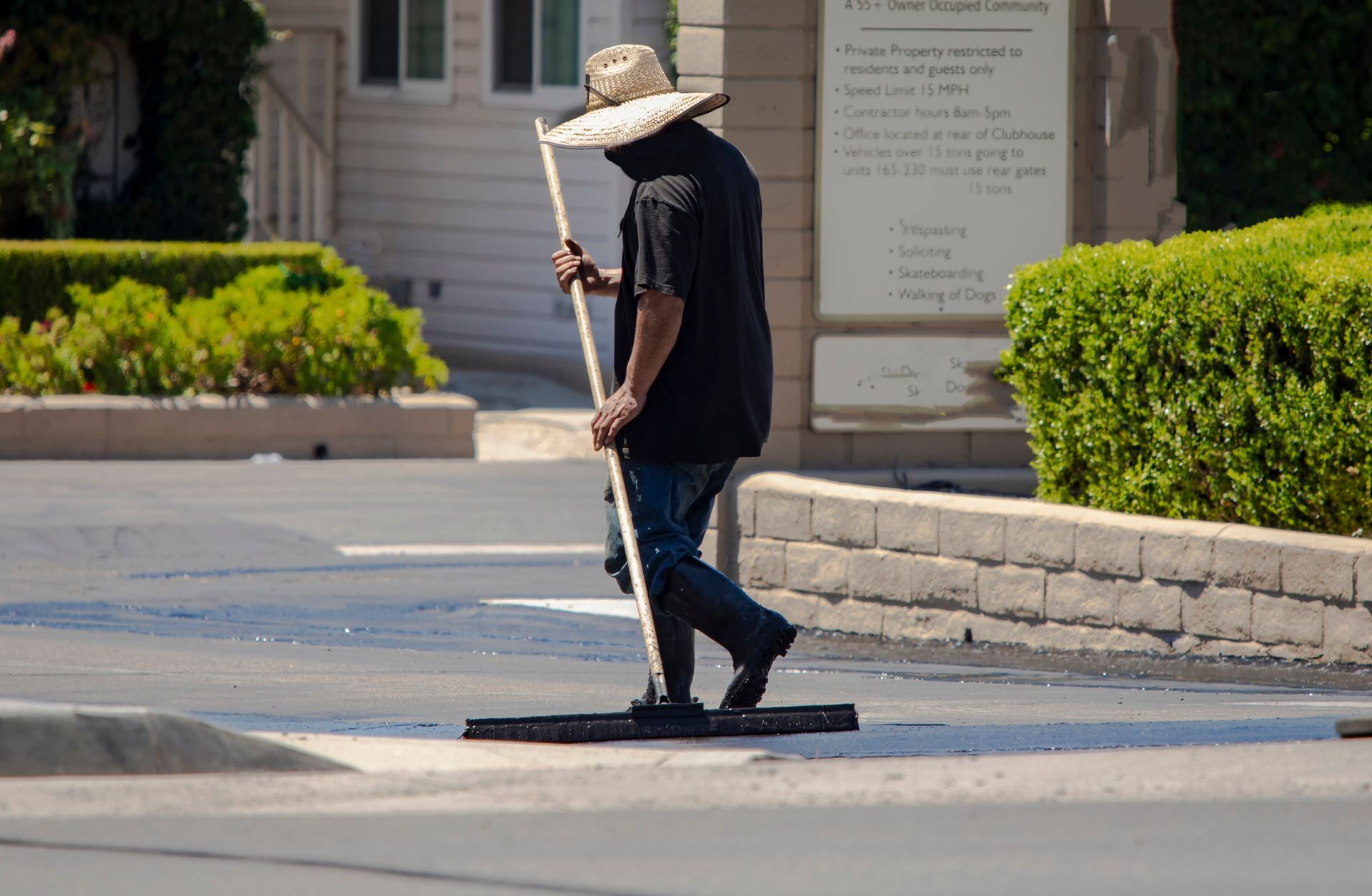 A person is spreading black paint on a concrete surface.
