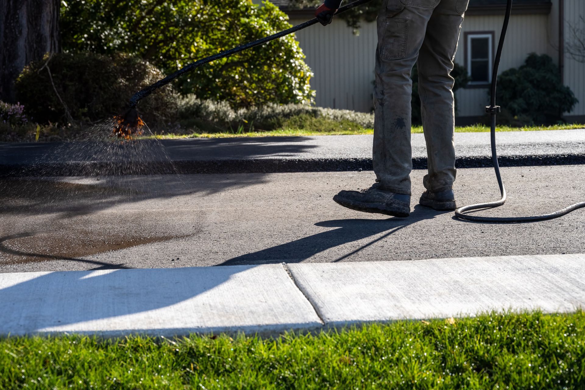 A person is spreading black paint on a concrete surface.