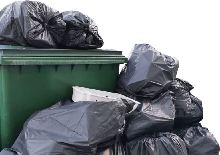 Green trash bin overflowing with black trash bags.