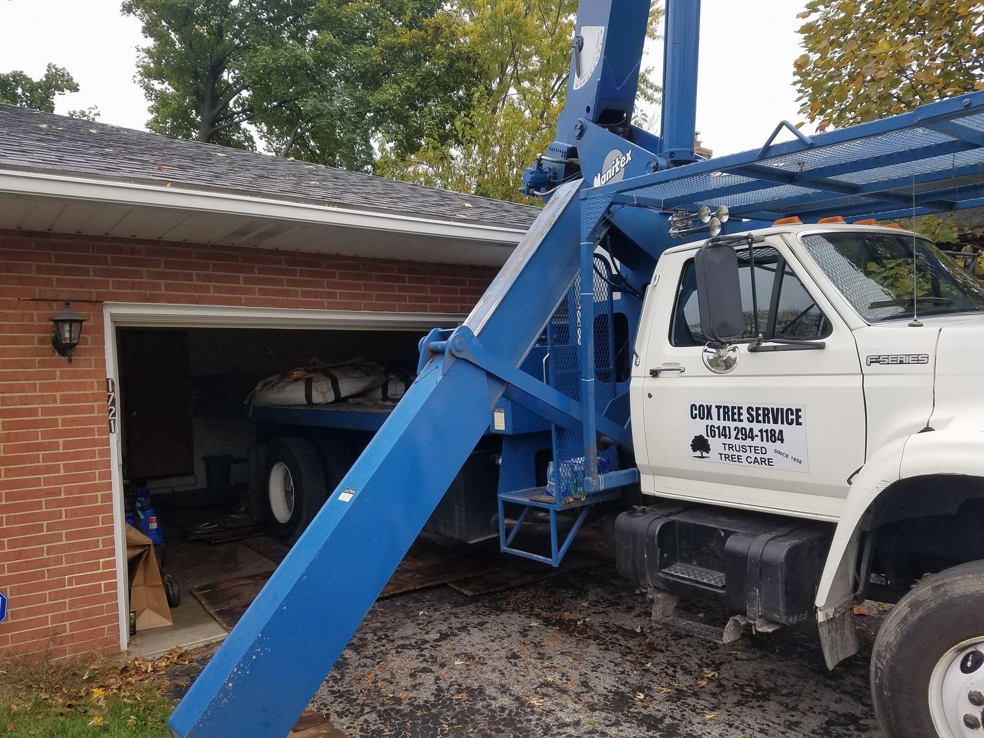 A blue and white truck is parked in front of a brick house.