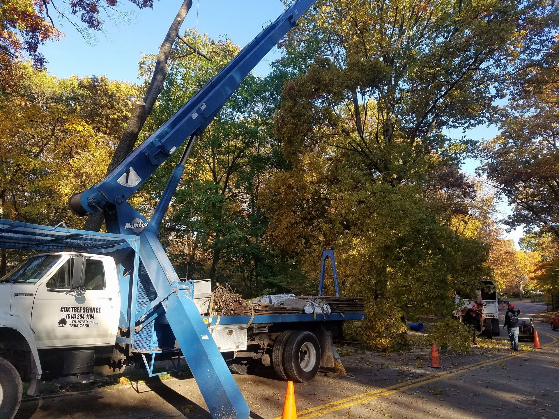 A blue truck with a crane attached to it is parked in a parking lot.