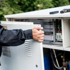 Apex Climate Control - A man is opening a cabinet with a screwdriver in it.