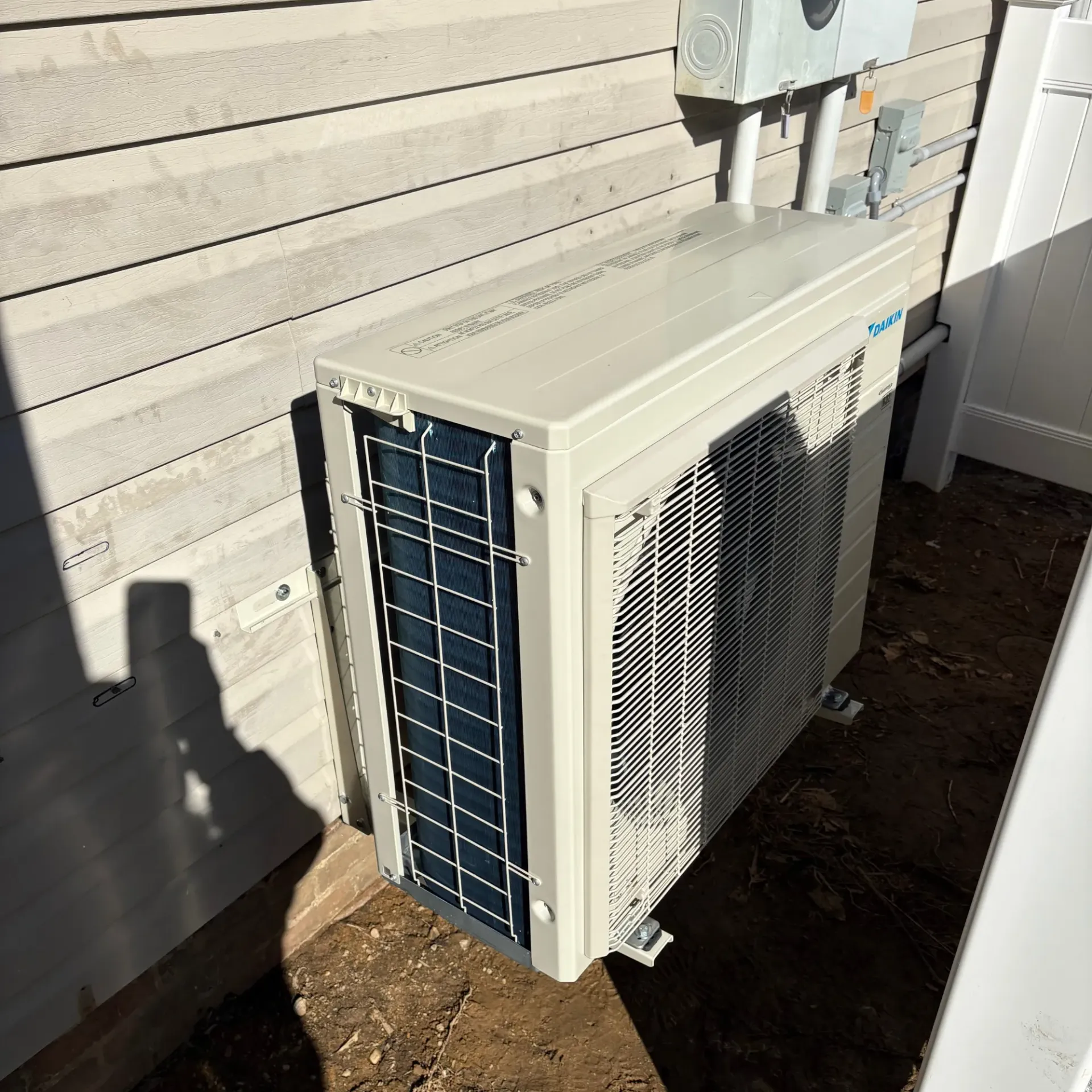 Apex Climate Control - A white air conditioner is sitting on the side of a house.