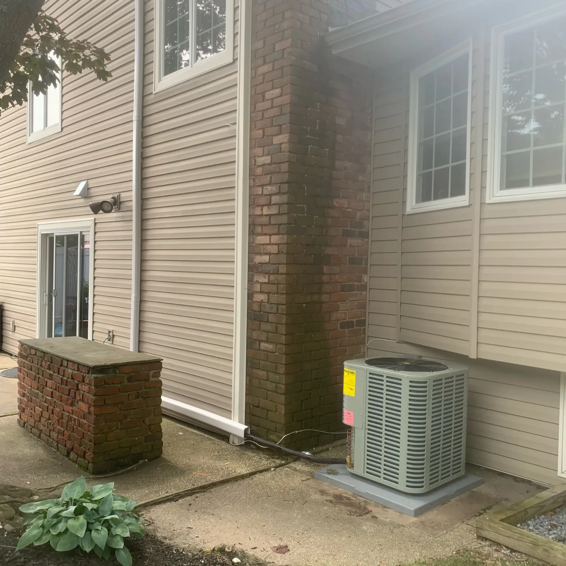 Apex Climate Control - A house with a brick chimney and a large air conditioner on the side of it.