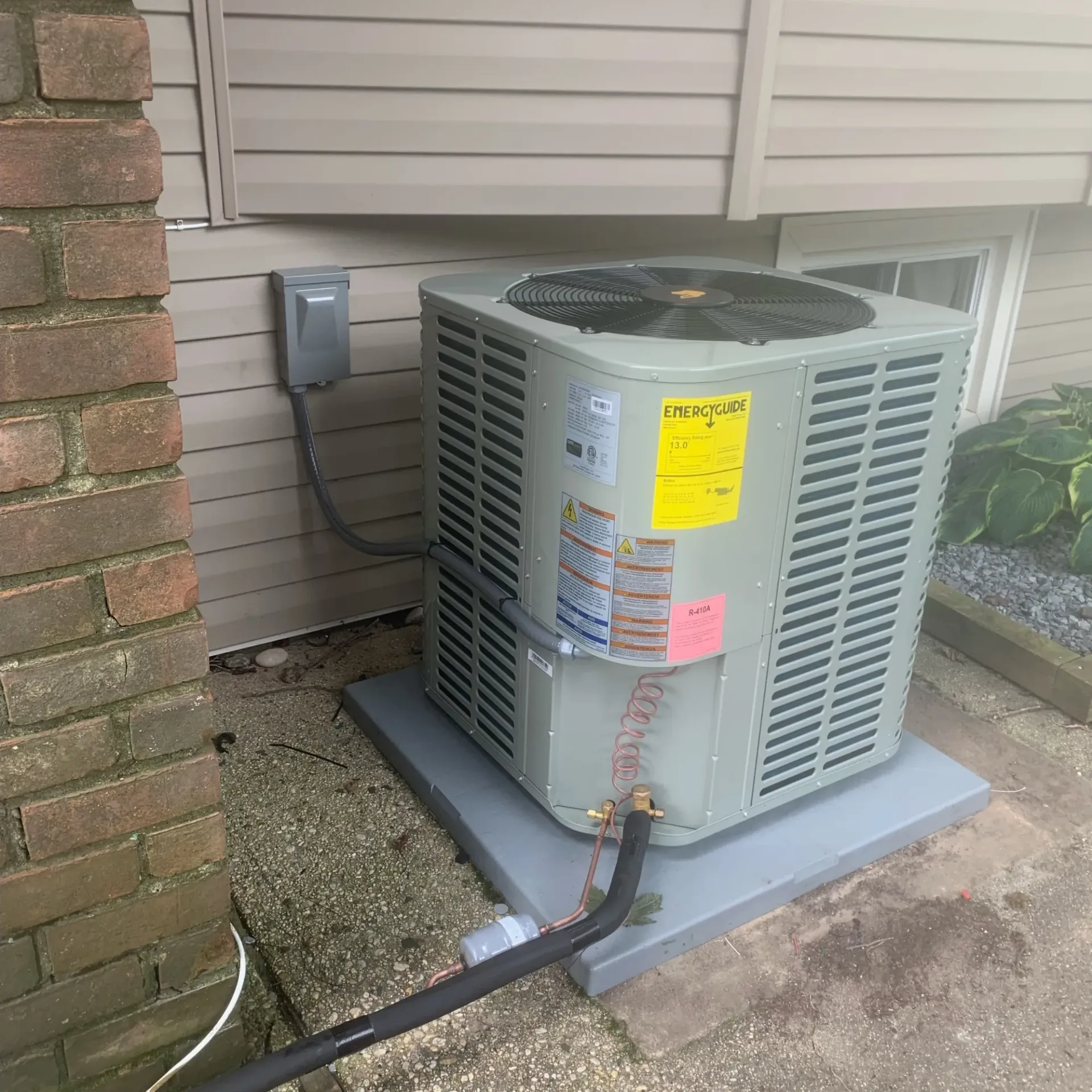 Apex Climate Control - An air conditioner is sitting outside of a house next to a brick wall.