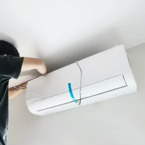 Apex Climate Control - A man is installing an air conditioner on the ceiling.