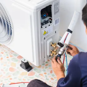 Apex Climate Control - A man is working on an air conditioner on the floor.