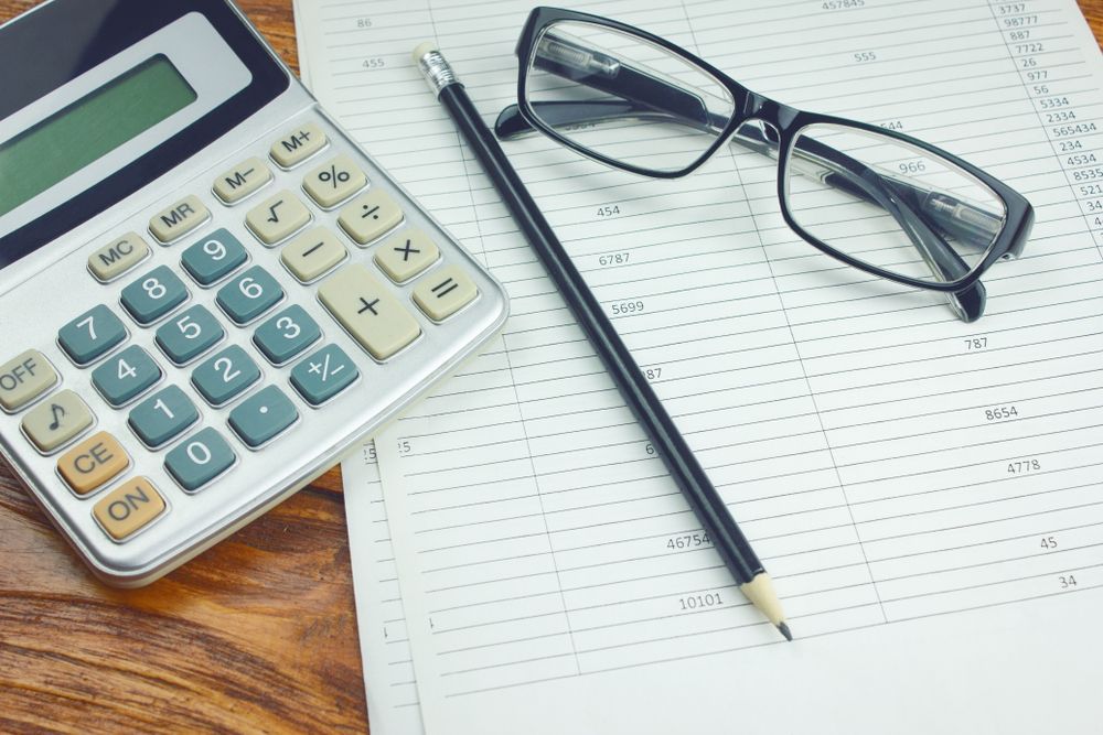 A Calculator , Pencil , And Glasses Are On A Wooden Table — Scott Kennedy's Landscape & Garden Supplies In Shaw, QLD