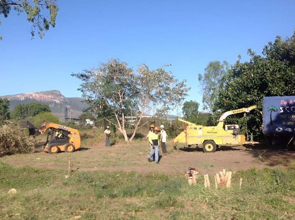 A Group Of People Are Standing In A Field With A Tractor — Scott Kennedy's Landscape & Garden Supplies In Shaw, QLD