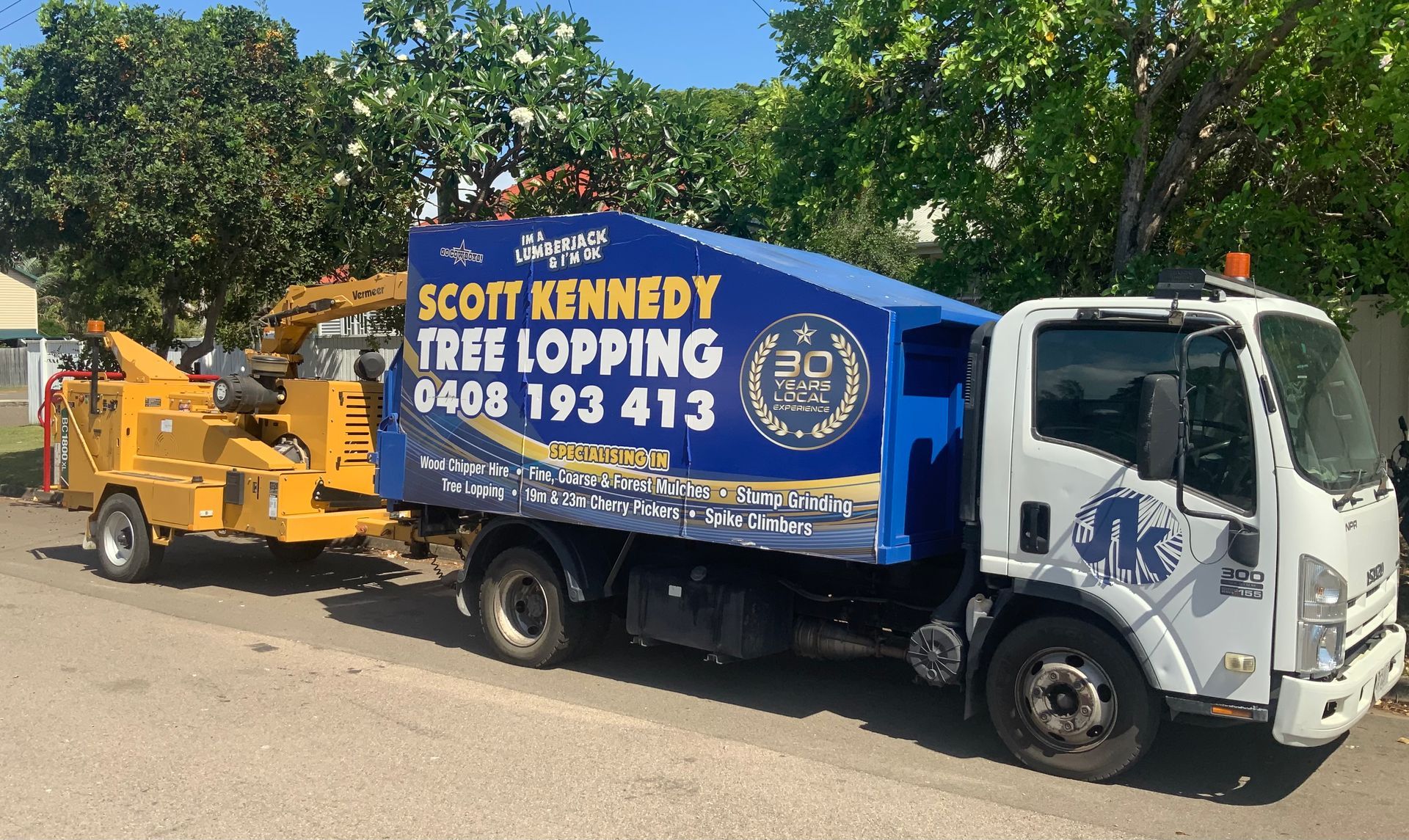 A Man Is Cutting A Tree With A Machine — Scott Kennedy's Landscape & Garden Supplies In Shaw, QLD