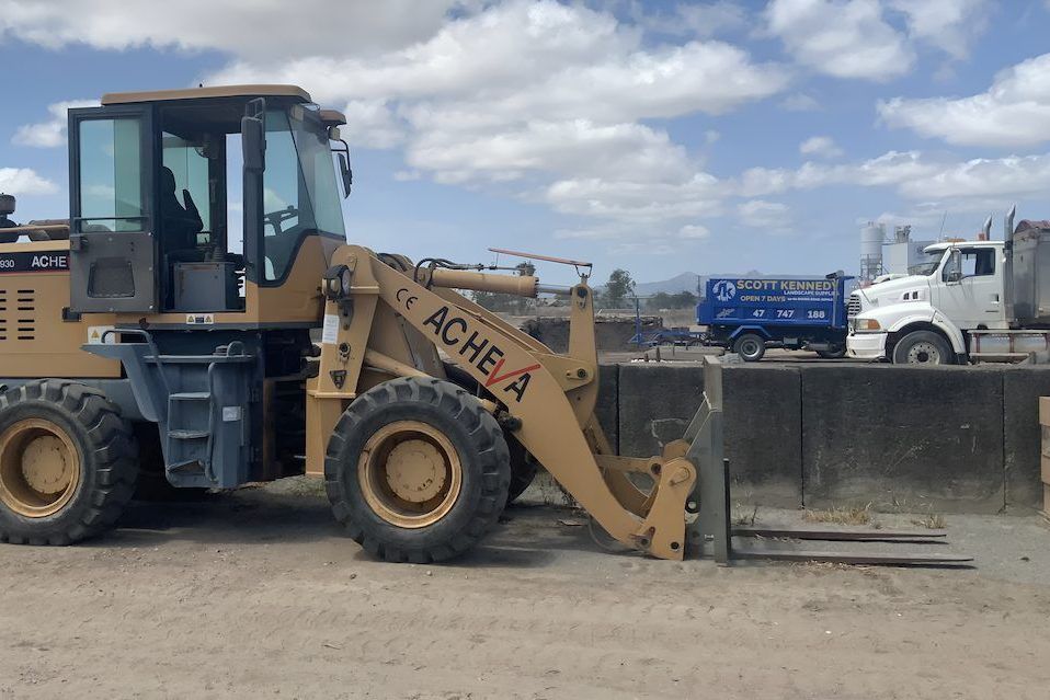 An Ache A Tractor Is Parked Next To A Truck — Scott Kennedy's Landscape & Garden Supplies In Shaw, QLD