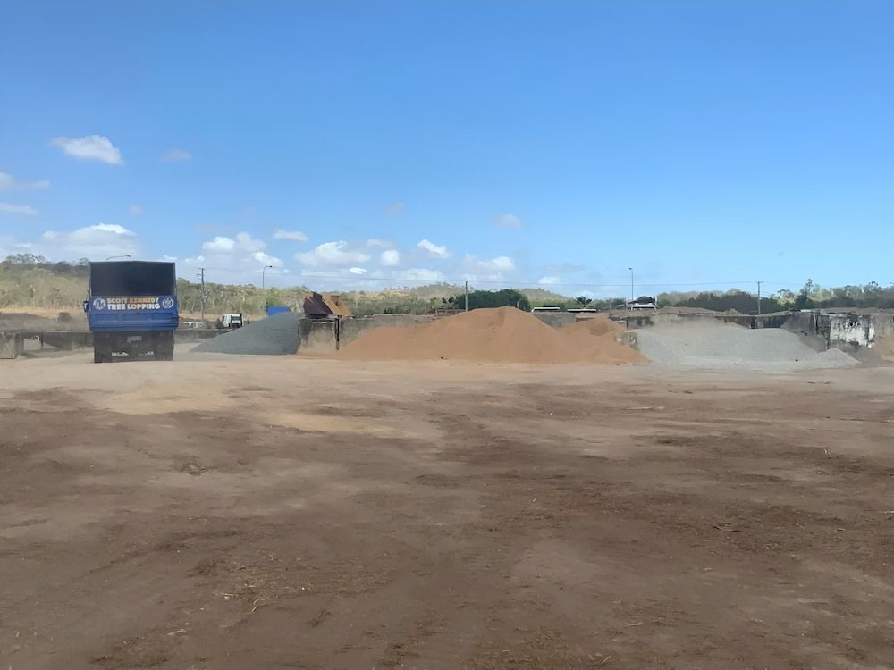 A Dump Truck Is Driving Down A Dirt Road Next To A Pile Of Dirt — Scott Kennedy's Landscape & Garden Supplies In Shaw, QLD