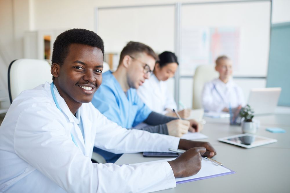 A group of doctors are sitting at a table in a conference room.