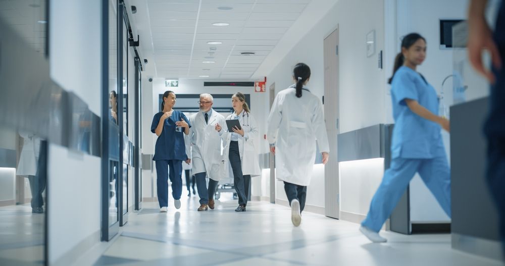 A group of doctors and nurses are walking down a hospital hallway.