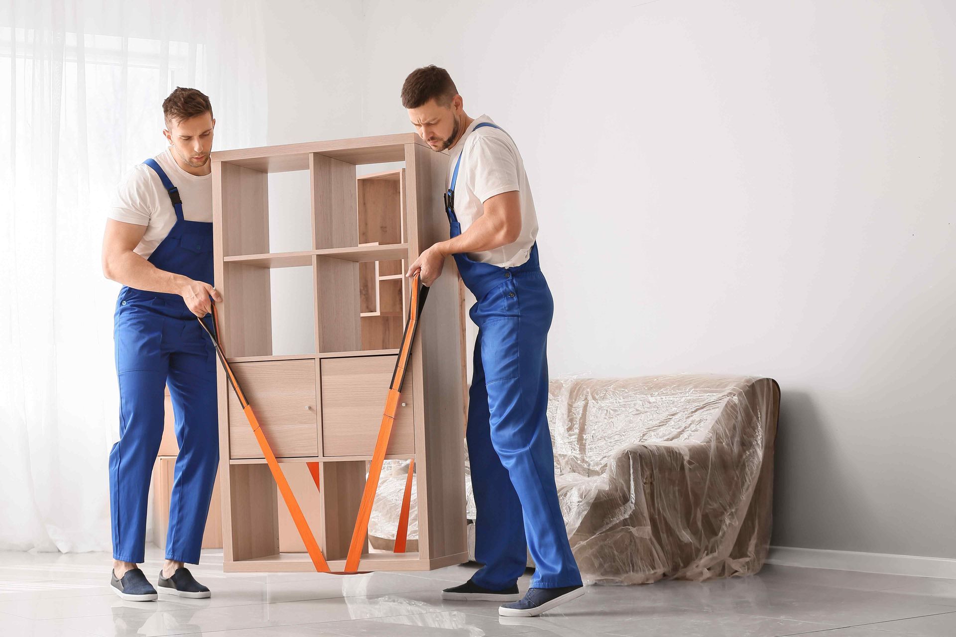 two movers are moving shelf with strap