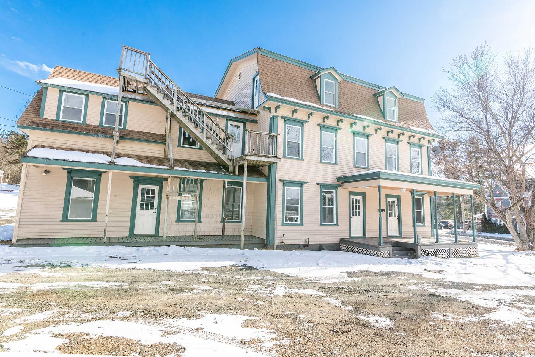 Large historic house with snow-covered yard and bare trees during winter