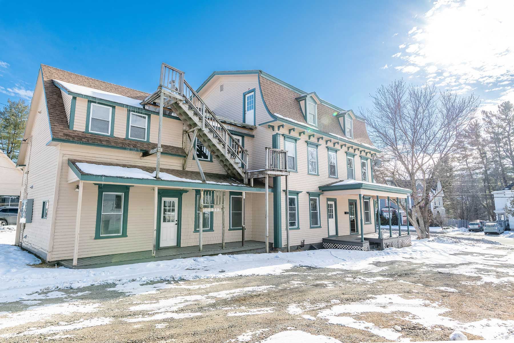 Snowy two-story apartment building with exterior stairs and green-trimmed windows