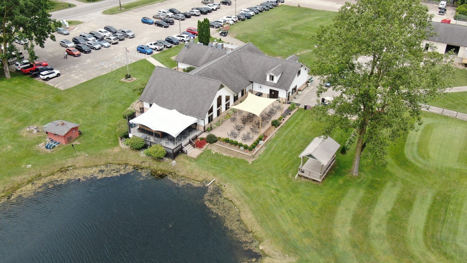 An aerial view of a golf course with a house and a pond.