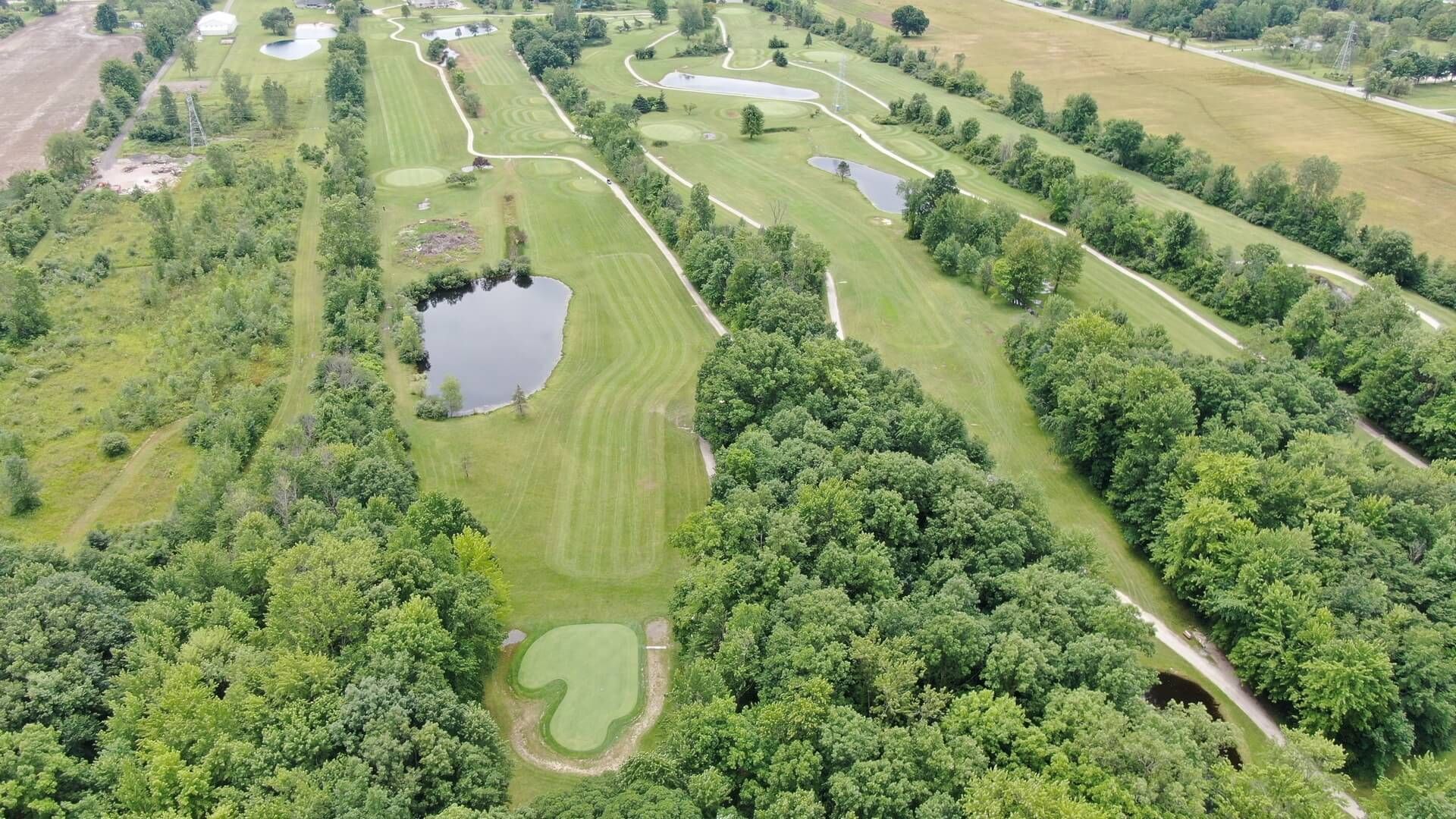 An aerial view of a golf course surrounded by trees and water.