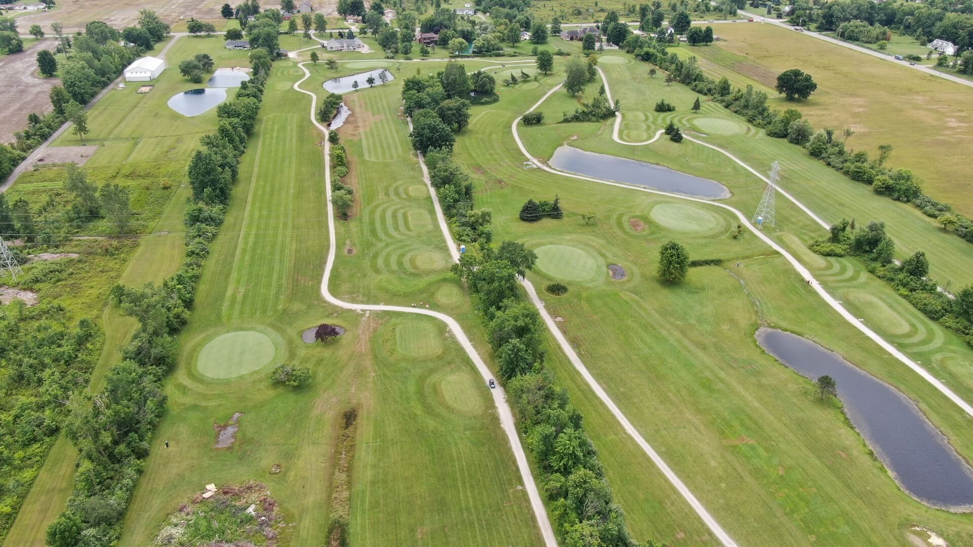 An aerial view of a golf course surrounded by trees and water.