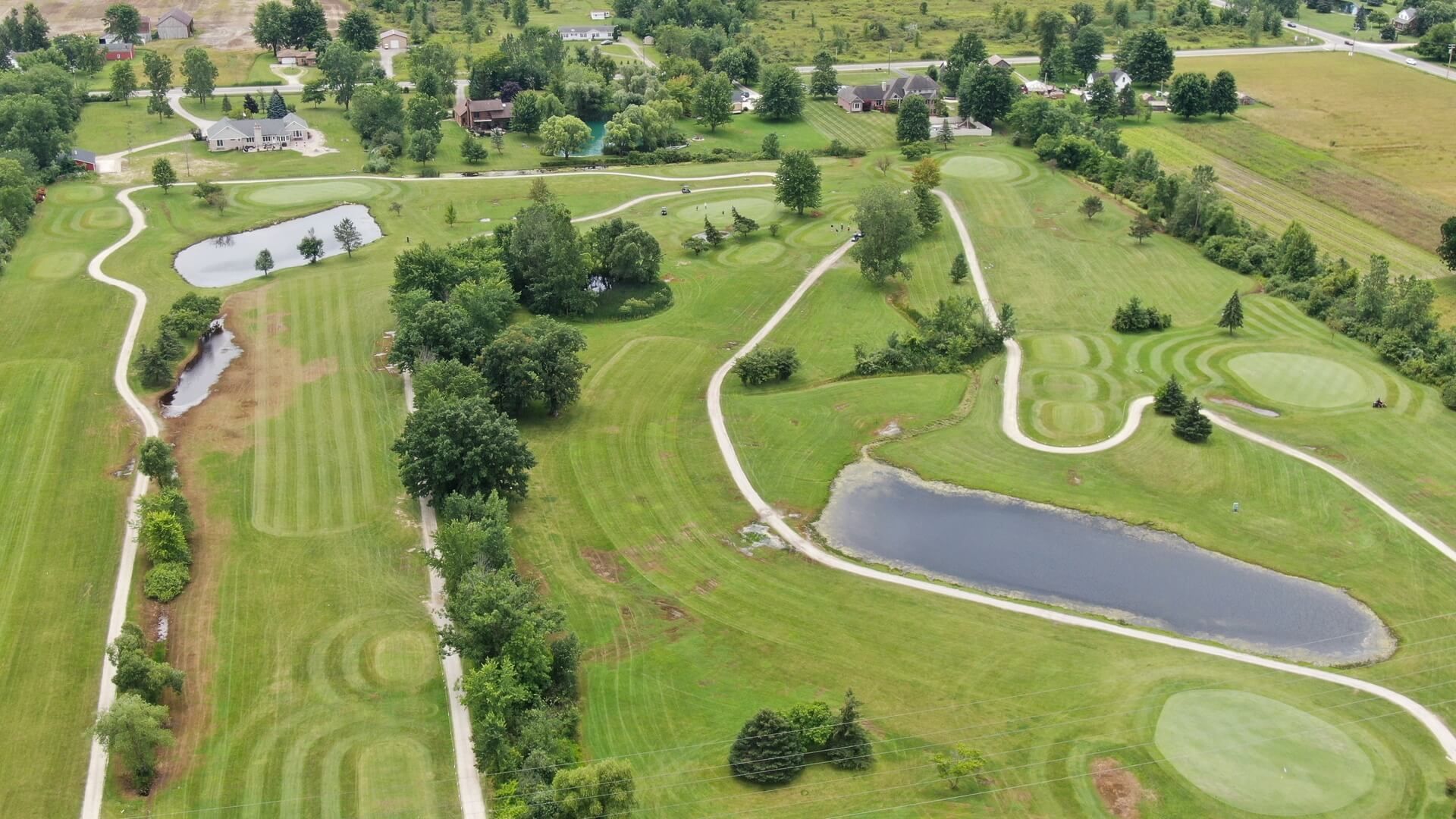 An aerial view of a golf course with a pond in the middle.
