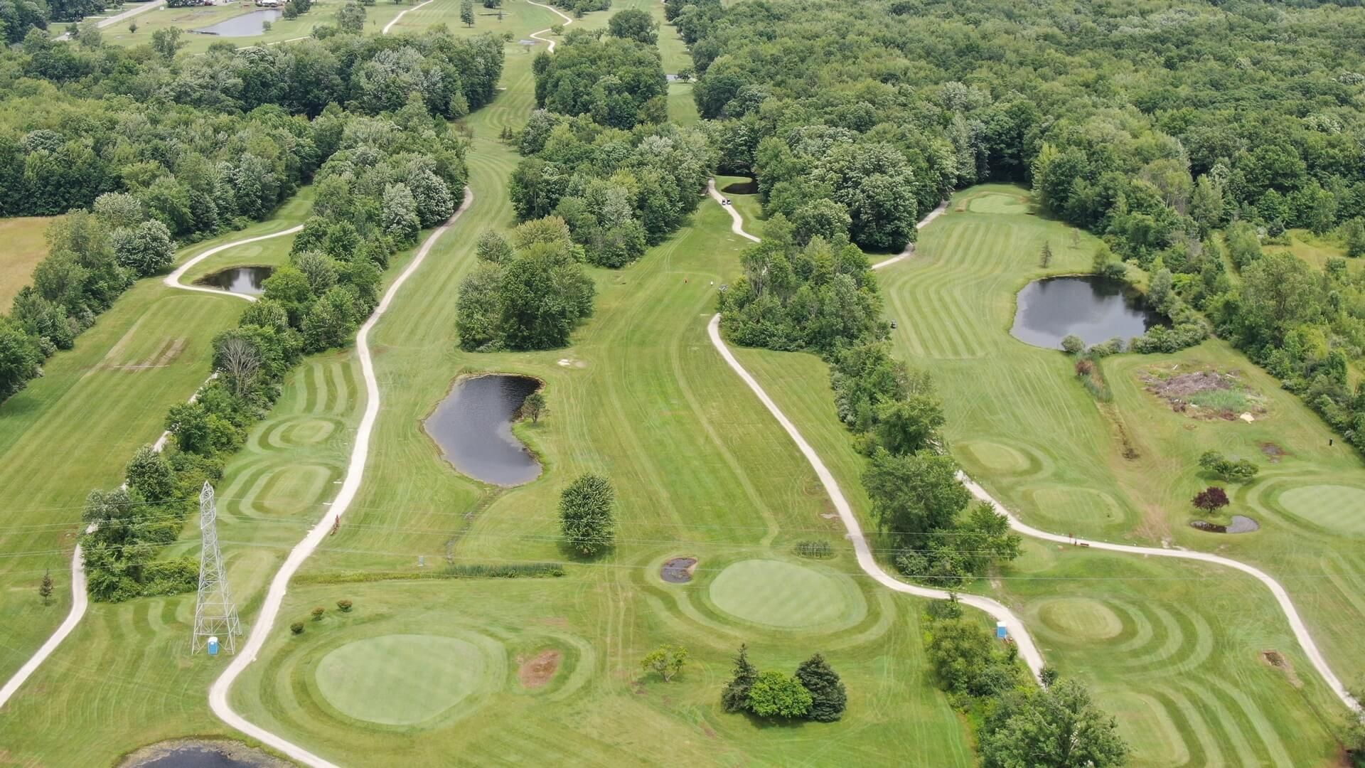 An aerial view of a golf course surrounded by trees and water.