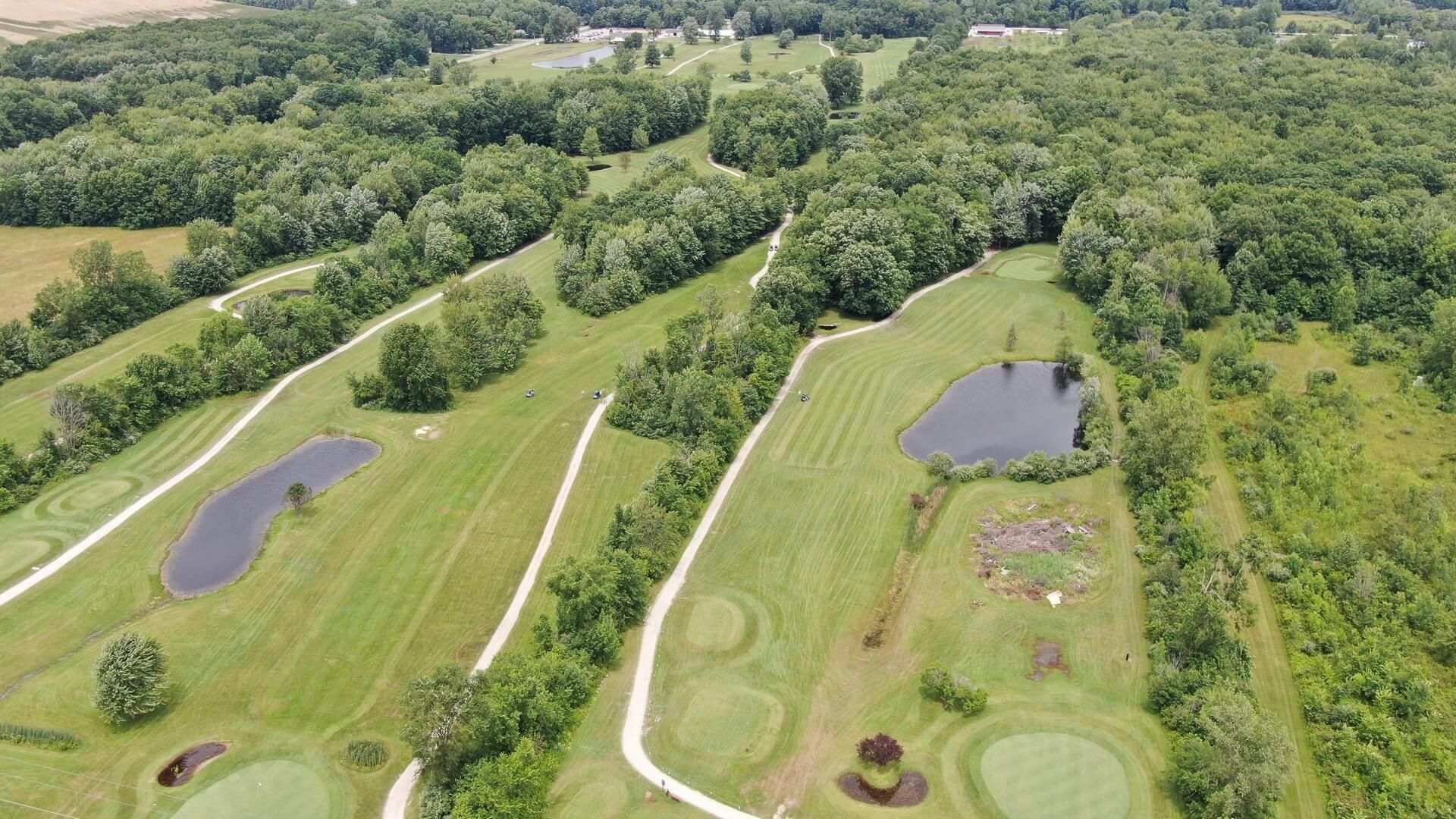 An aerial view of a golf course surrounded by trees and ponds.