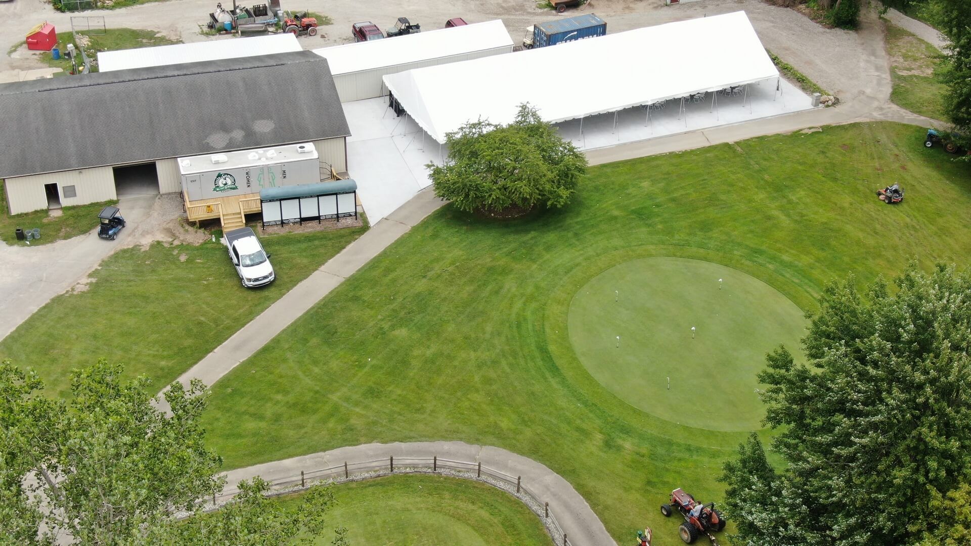 An aerial view of a lush green field with a white tent in the middle.