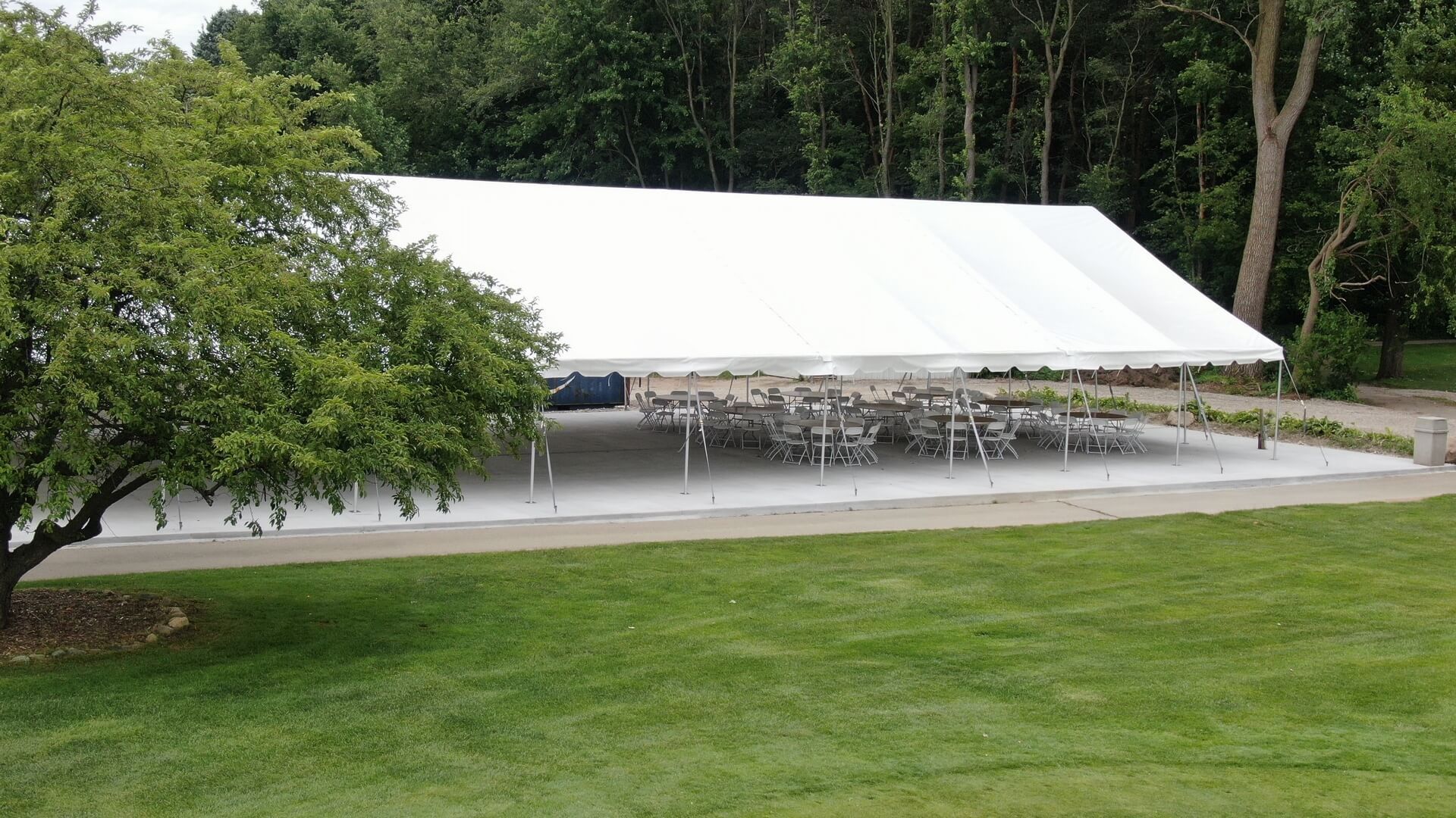 A large white tent with tables and chairs underneath it.