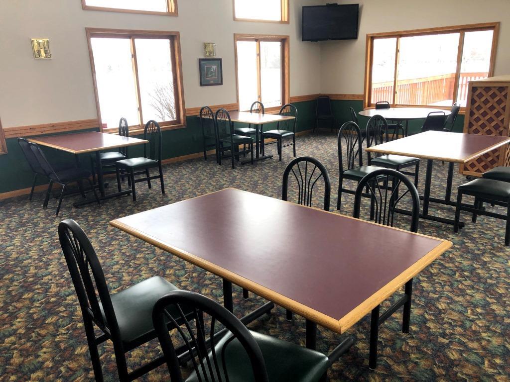 A restaurant with tables and chairs and a television on the wall.