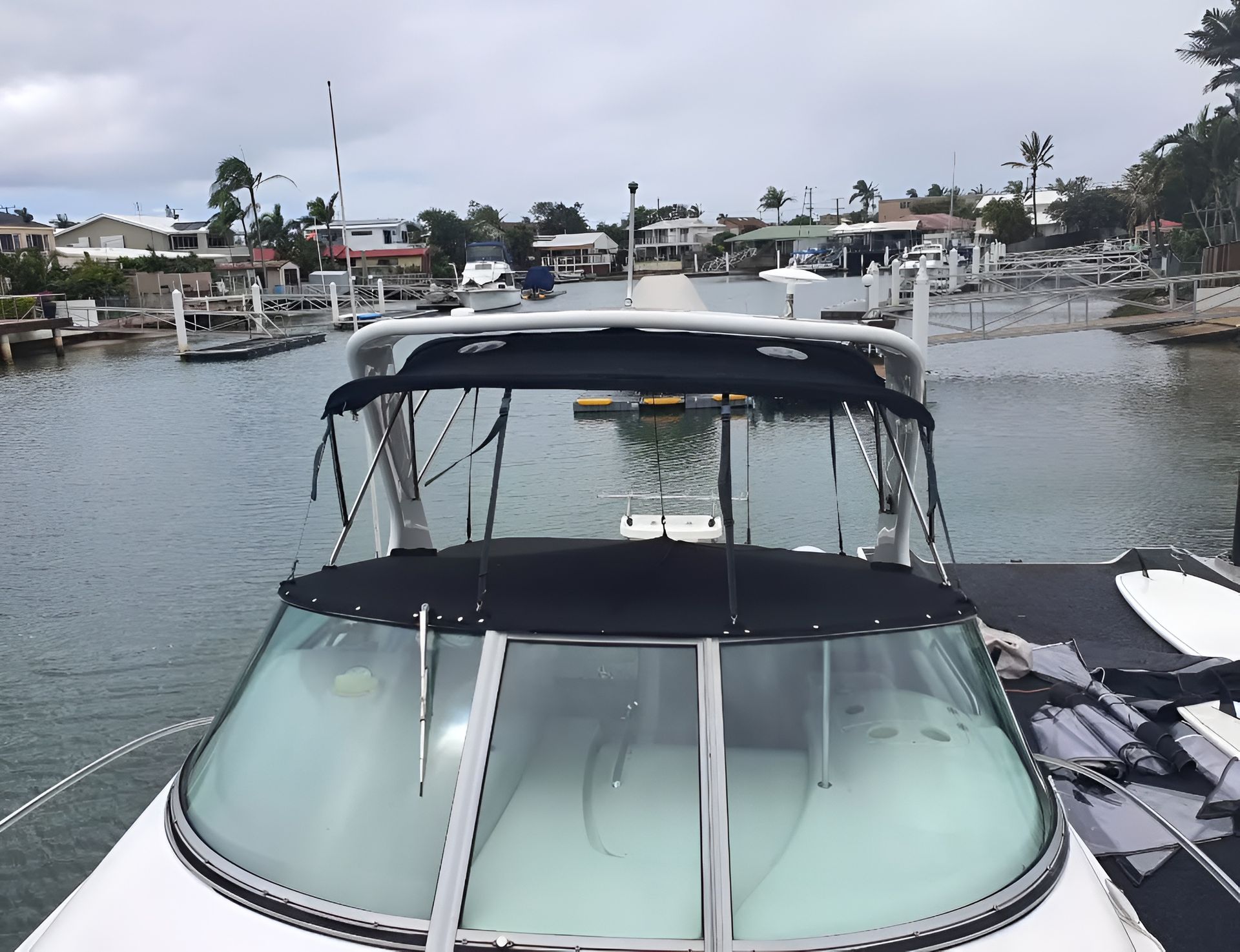 A Boat With a Black Canopy in a Harbor, With Houses — The Boat Cover Company In Buddina, QLD