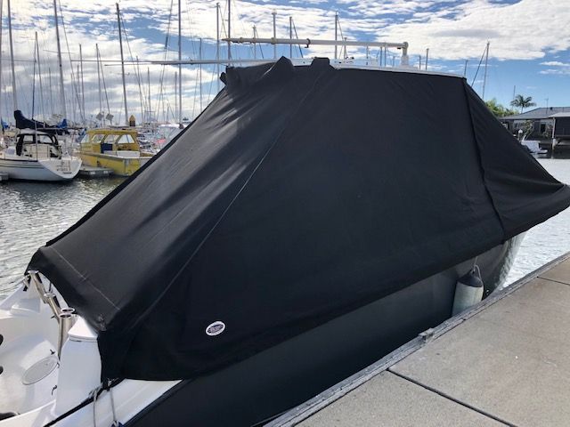 A Boat Is Docked At A Dock With A Black Cover On It — The Boat Cover Company In Buddina, QLD