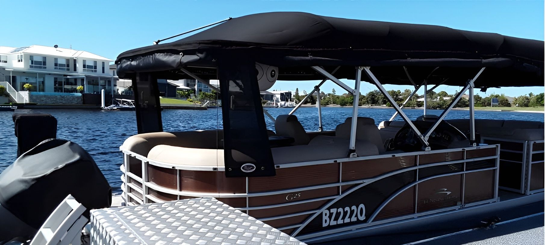 A Pontoon Boat is Docked in a Waterway on a Sunny Day — The Boat Cover Company In Buddina, QLD