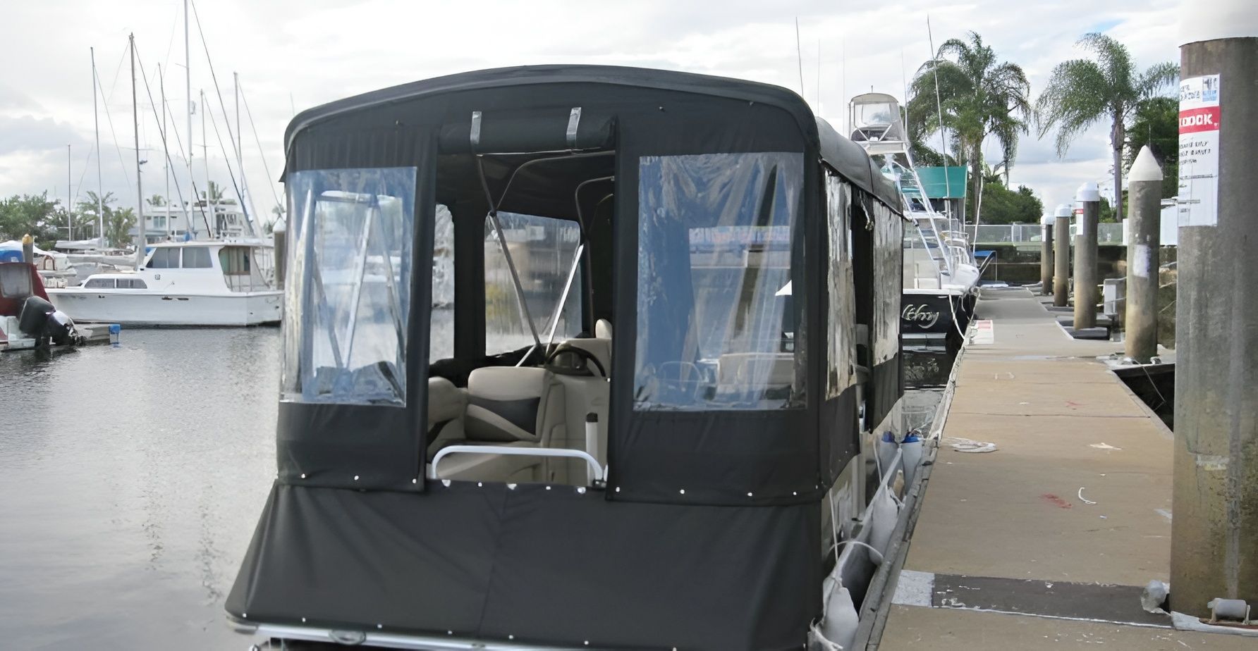 Black-covered Pontoon Boat Docked at a Marina With Clear Plastic Windows — The Boat Cover Company In Buddina, QLD