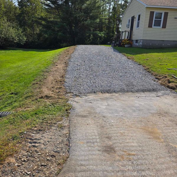 A gravel driveway with a house in the background