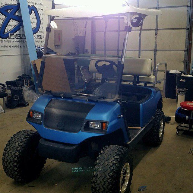 A blue golf cart is parked in a garage