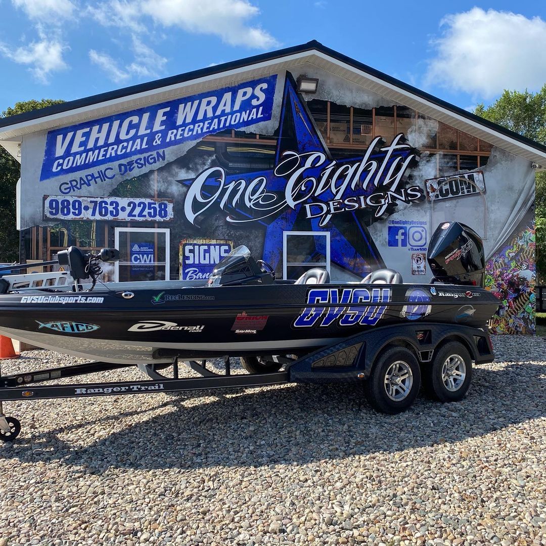 A boat is parked in front of a building that says vehicle wraps.