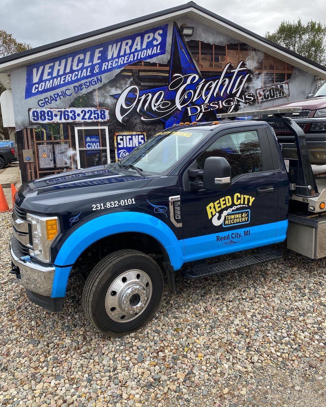 A blue and black tow truck is parked in front of a building.