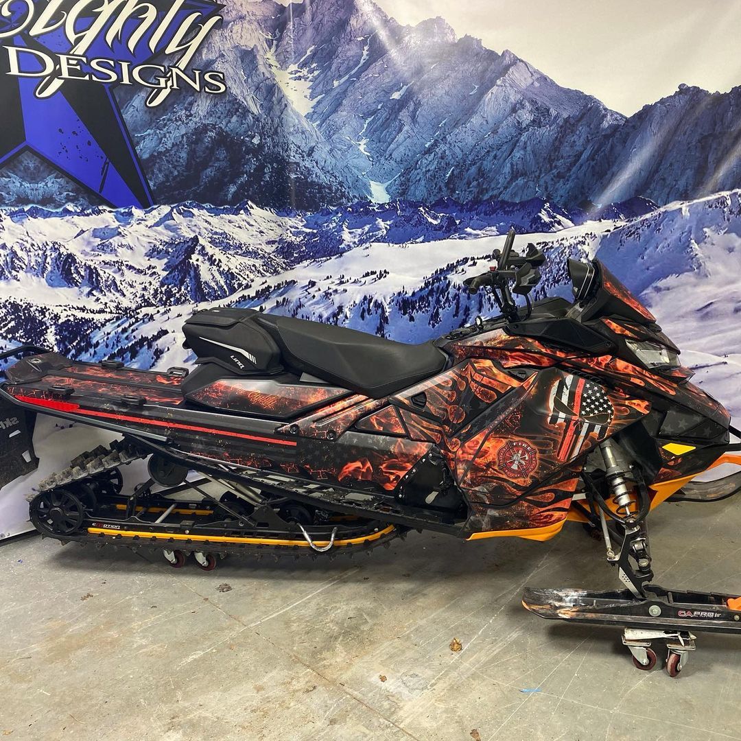A snowmobile is parked in front of a sign that says original designs