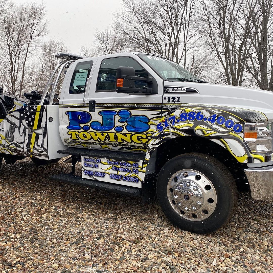 A white towing truck is parked on a gravel road.