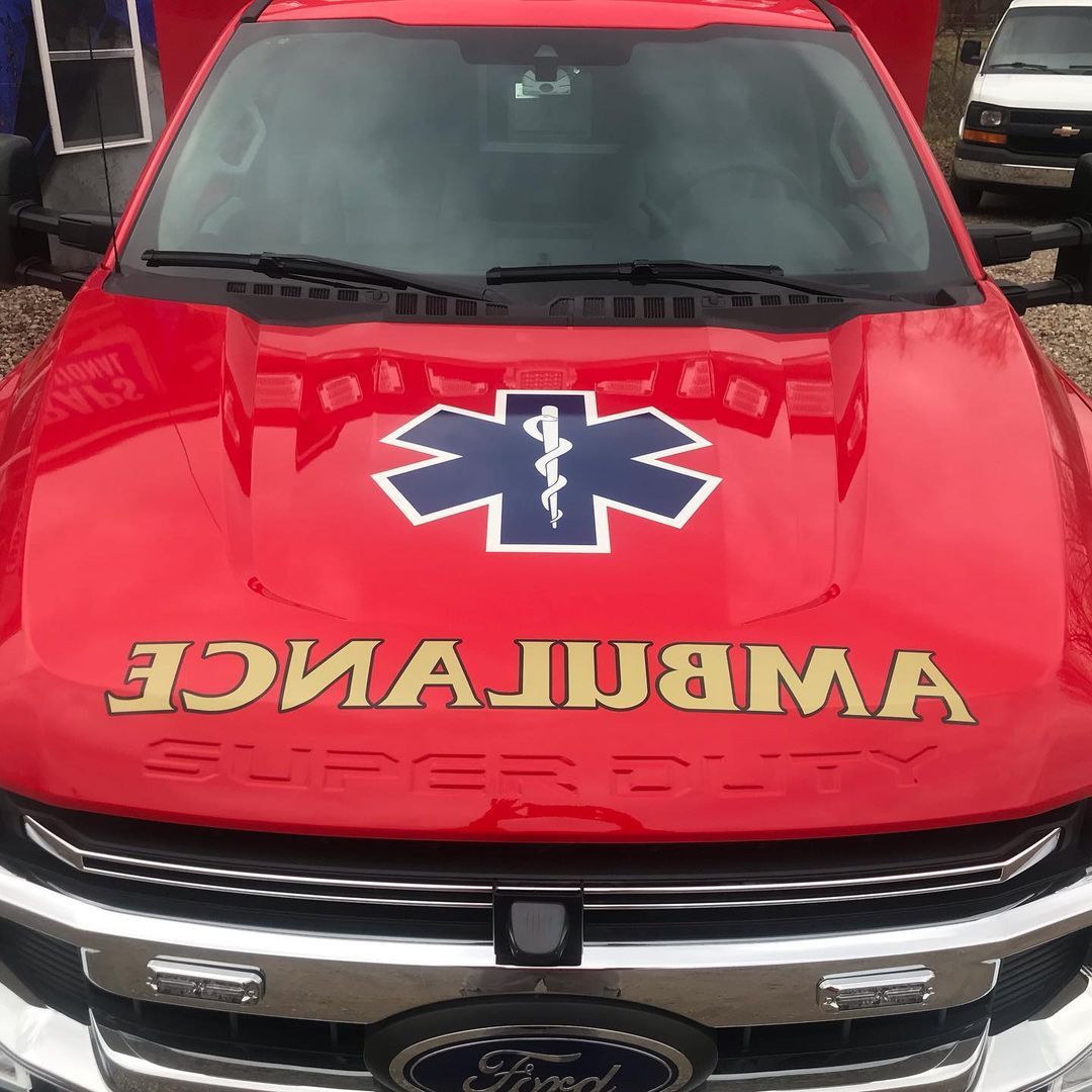 A red ambulance with the word ambulance on the hood