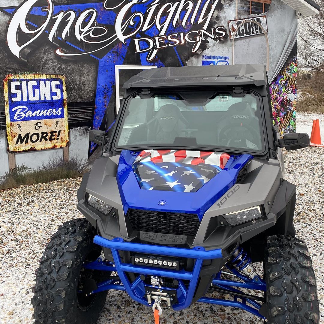 A blue and gray atv is parked in front of a building with signs on it.