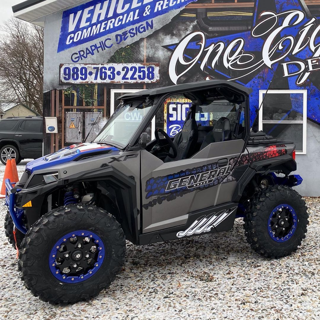 A gray and blue atv is parked in front of a building.