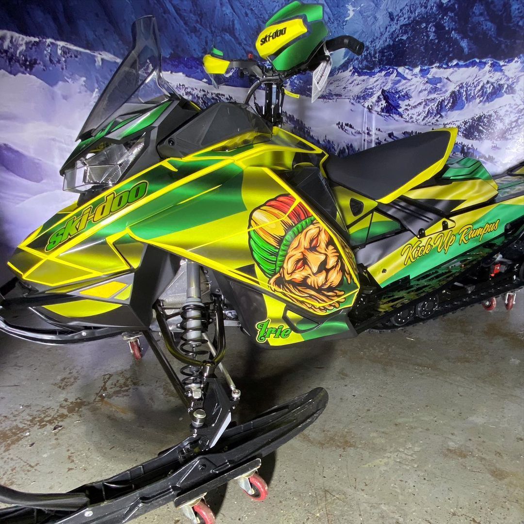 A yellow and green snowmobile is parked in a garage