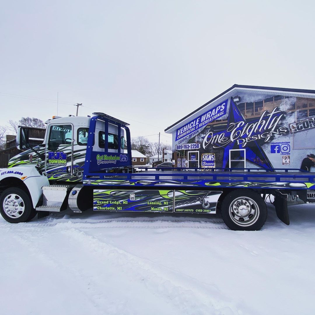 A tow truck is parked in the snow next to a building.