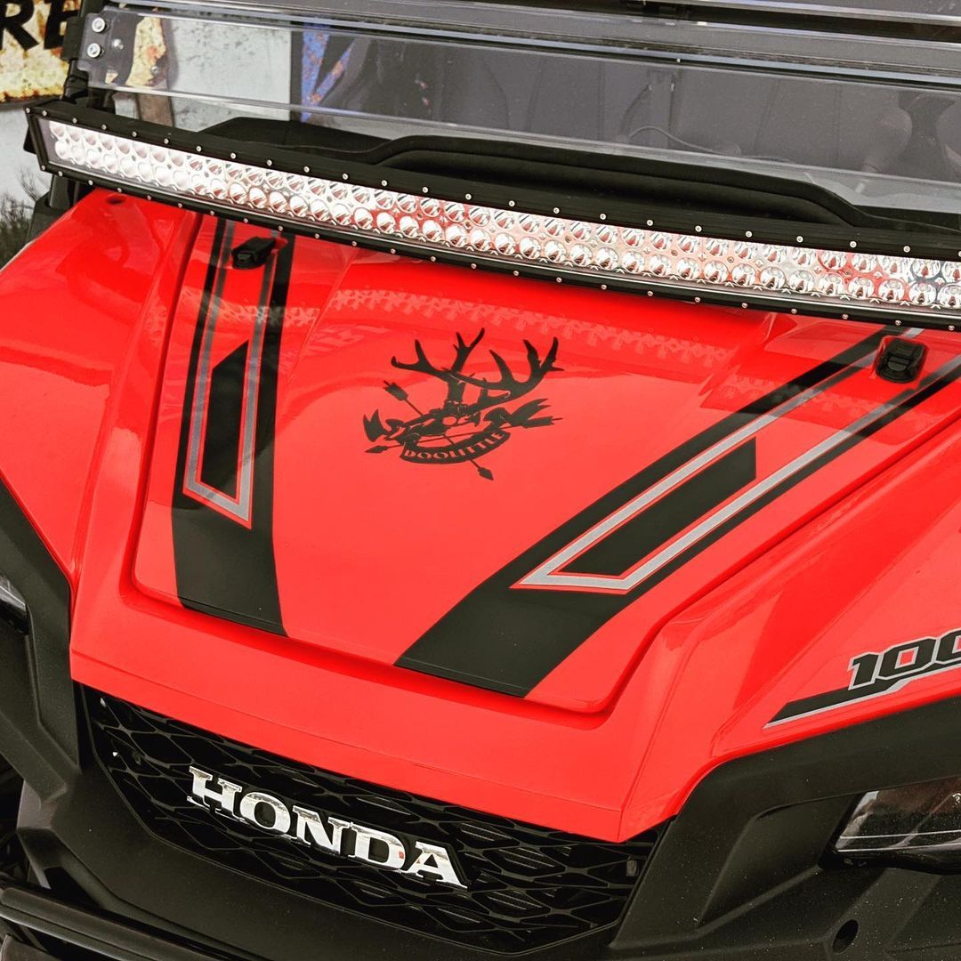A red honda golf cart with antlers on the hood