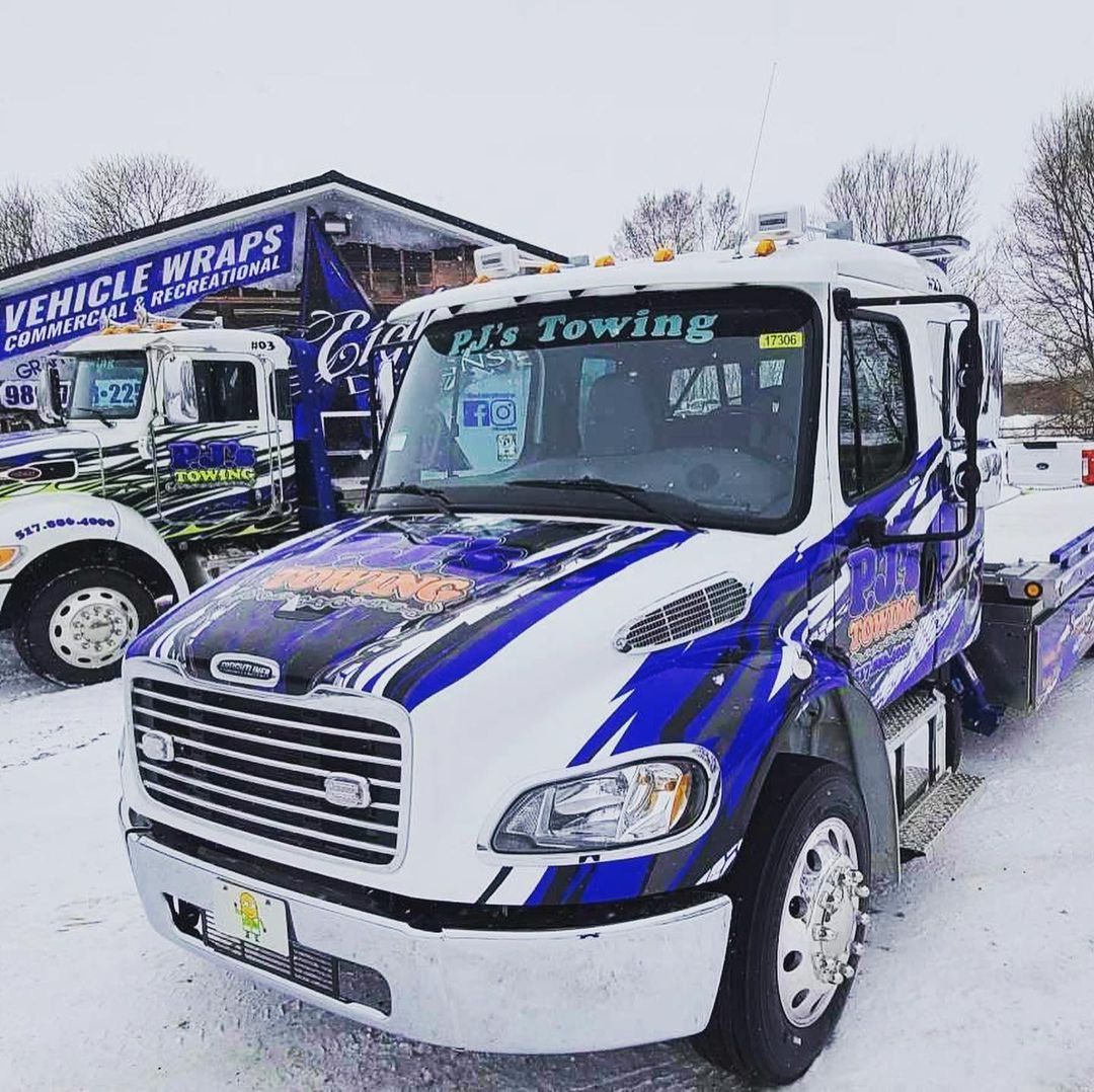 A blue and white tow truck is parked in the snow.