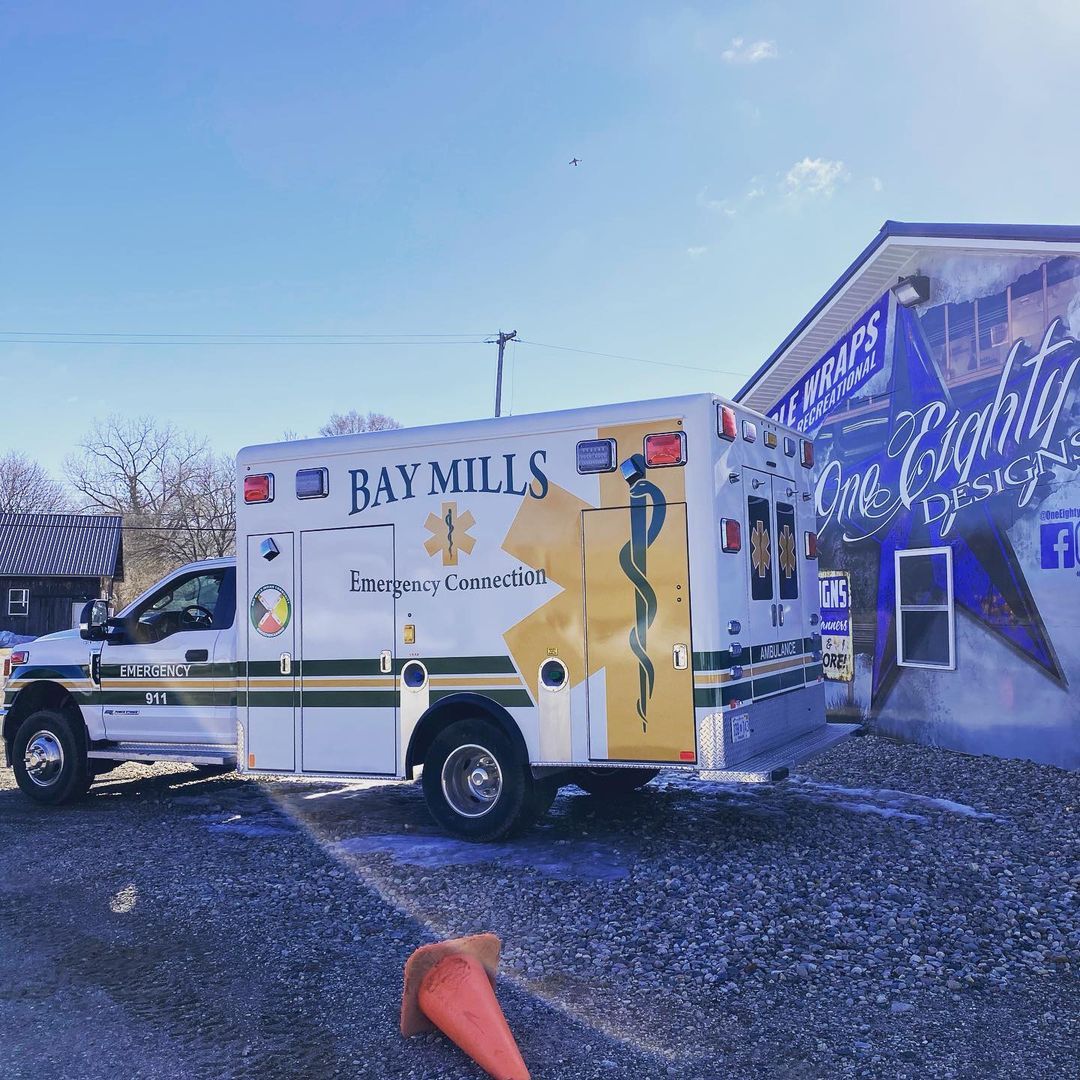 A bay mills ambulance is parked in front of a building